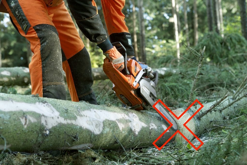 Close-up showing how the nose of the guide bar incorrectly is about to hit into the end of a lying log