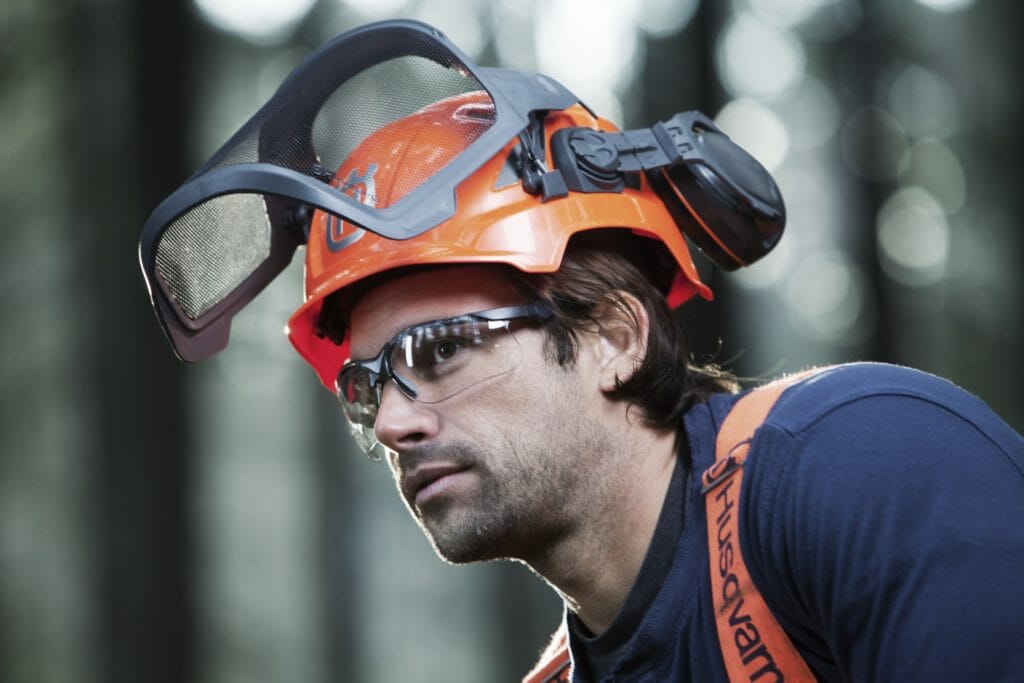 Close-up of forestry worker with protective glasses and a helmet with earmuffs and folded up visors