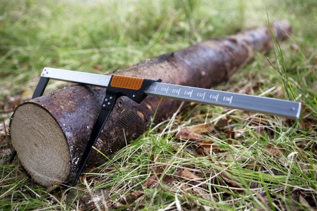A calliper measuring the diameter of a log on the ground