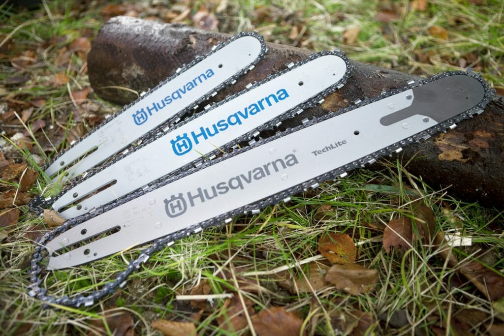 Tree chainsaw bars with chains lying on a log on the ground